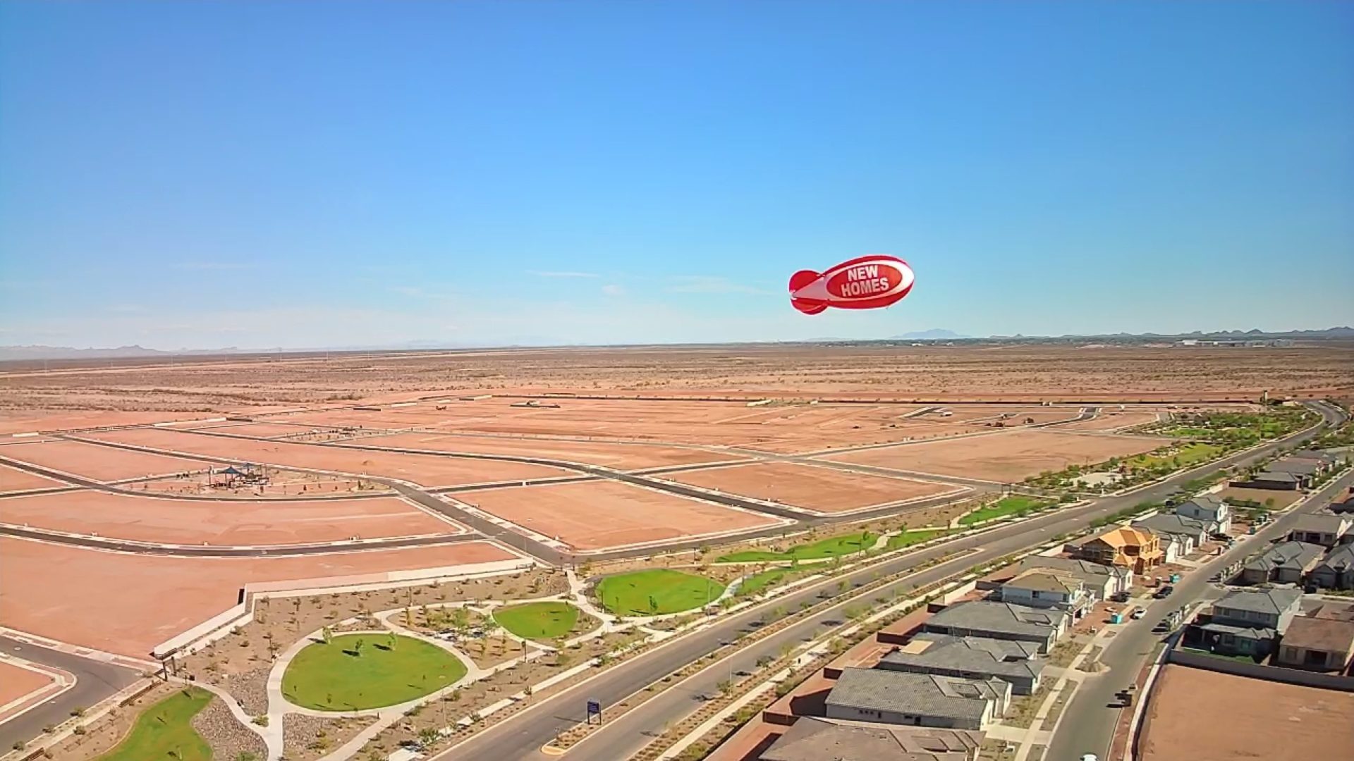 Red marketing blimp flying 120 feet above a new home development